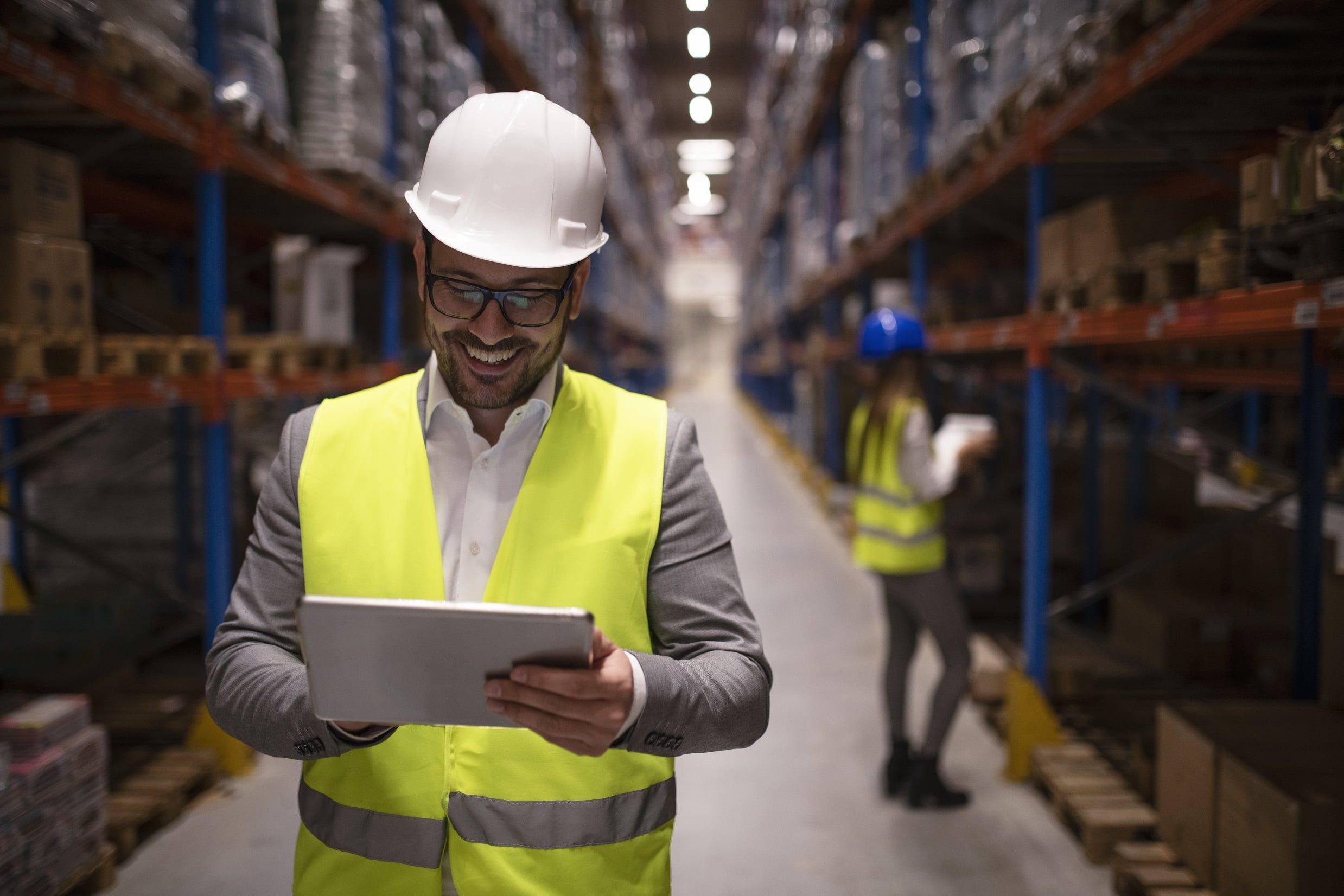 Warehouse supervisor reading report on tablet about successful delivery and distribution in warehouse logistics center.