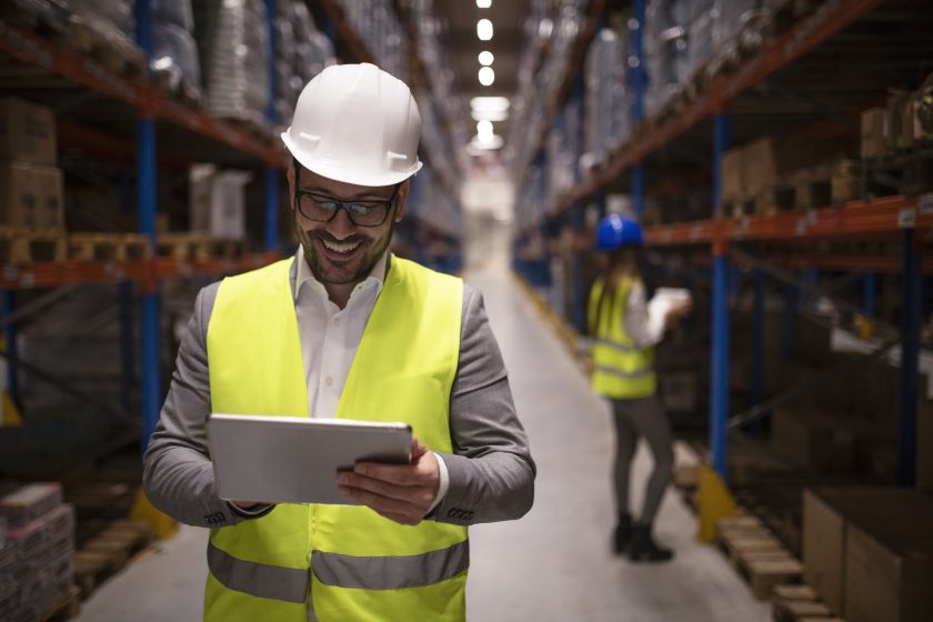 Warehouse supervisor reading report on tablet about successful delivery and distribution in warehouse logistics center.